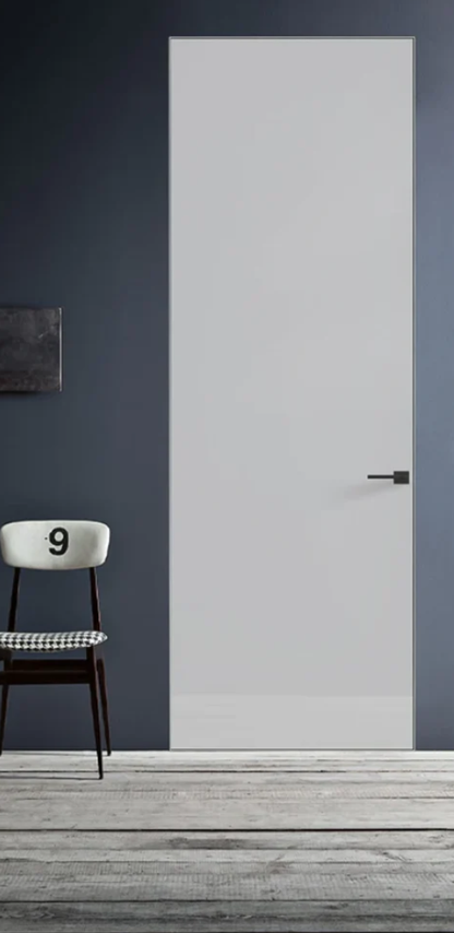 White door with a black handle on a dark gray wall with a chair and small table.